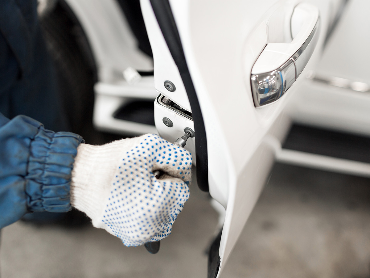 Automotive locksmith working on the lock of a car door.