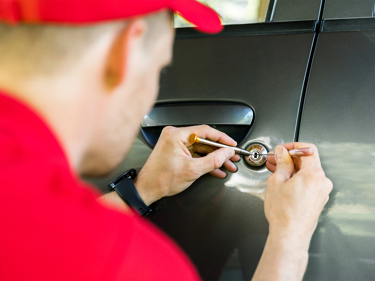 Locksmith working on the lock of a car.