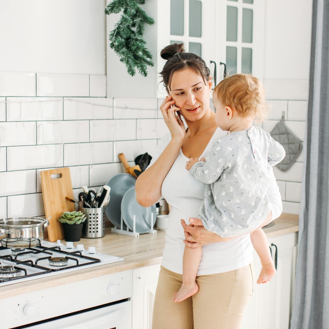 woman on phone holding a child
