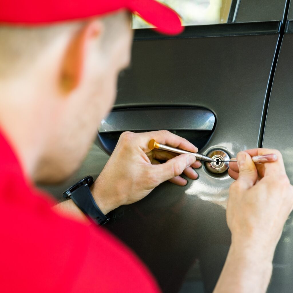A locksmith using tools to pick a car door lock.