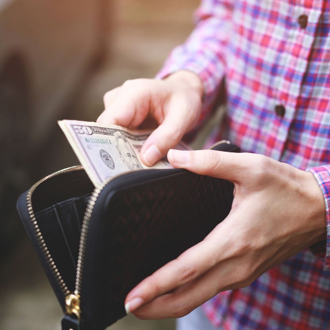 person putting money into their wallet